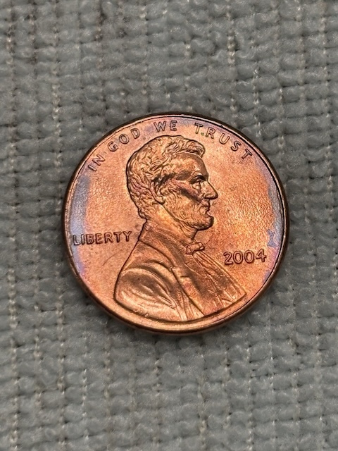 2004 penny lamination error showing peeling outer copper layer separating from zinc core on planchet surface